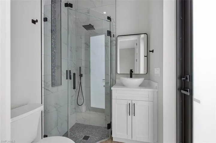 Bathroom with vanity and a marble finish shower