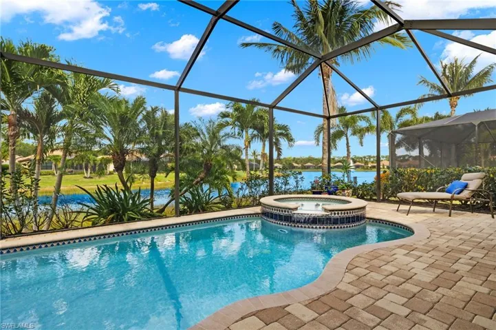View of pool featuring an in ground hot tub, a patio, a water view, and a lanai