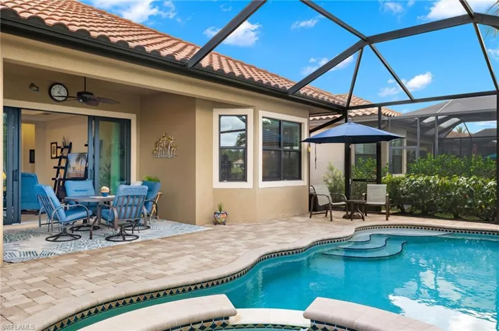View of swimming pool featuring glass enclosure, ceiling fan, and a patio area
