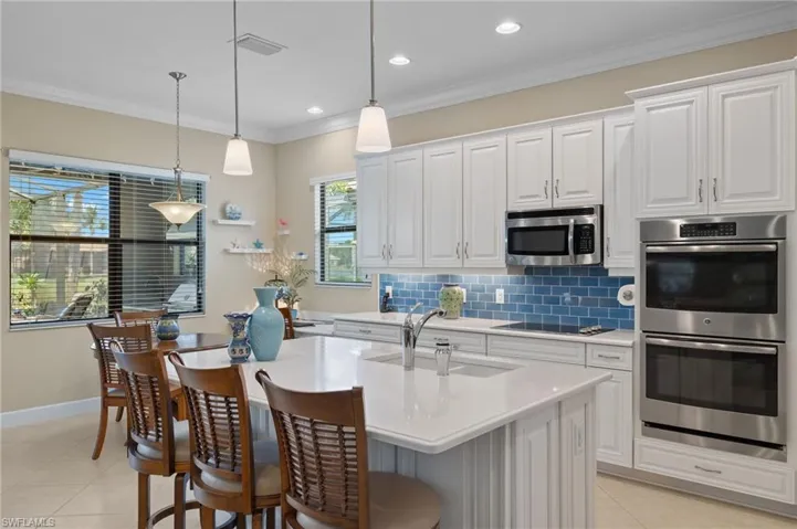 Kitchen featuring white cabinets, sink, appliances with stainless steel finishes, and a center island with sink