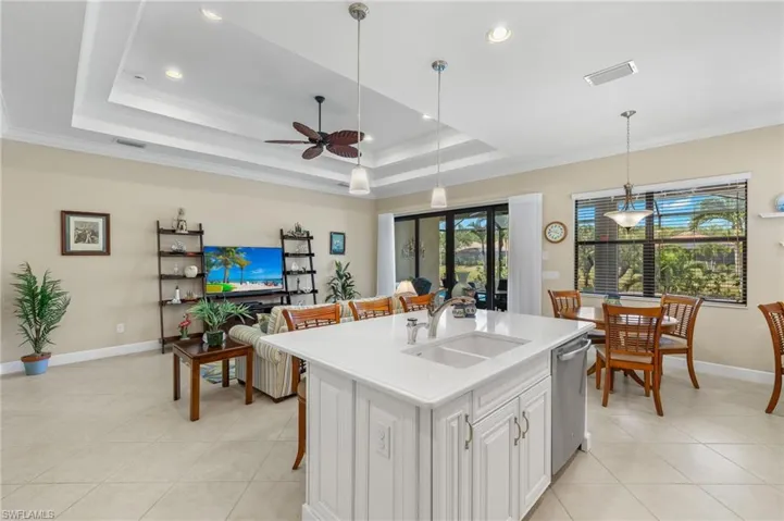 Kitchen featuring white cabinets, sink, pendant lighting, an island with sink, and ceiling fan