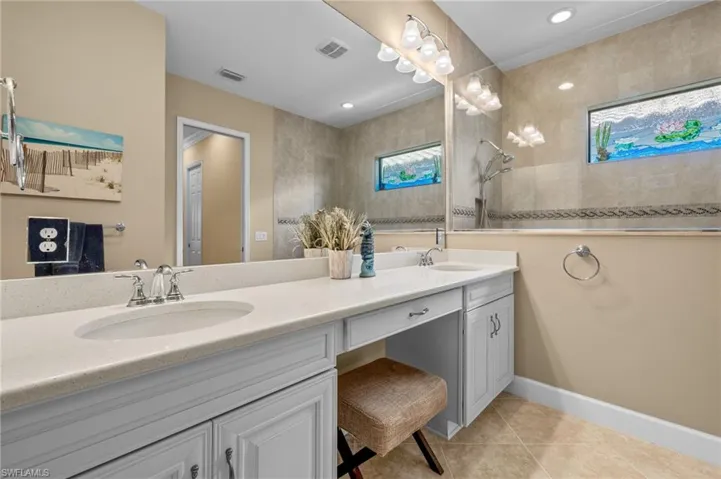 Bathroom featuring vanity, tiled shower, and tile patterned floors