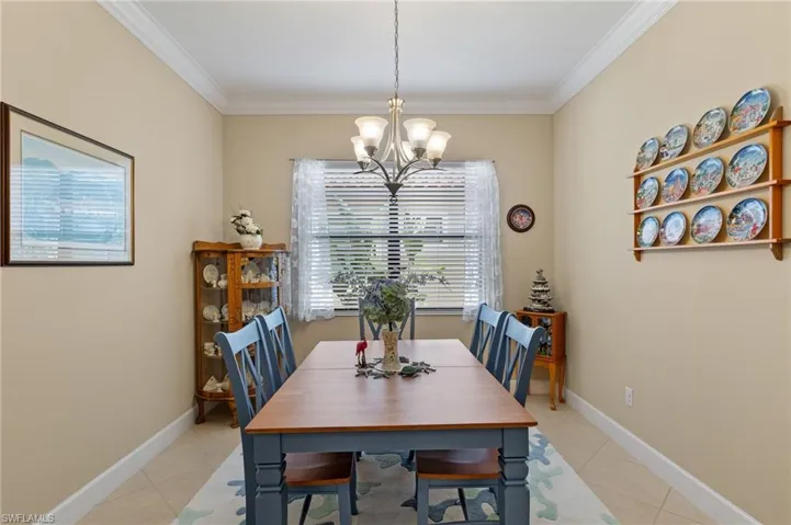 Dining area with light tile patterned floors, ornamental molding, and a notable chandelier