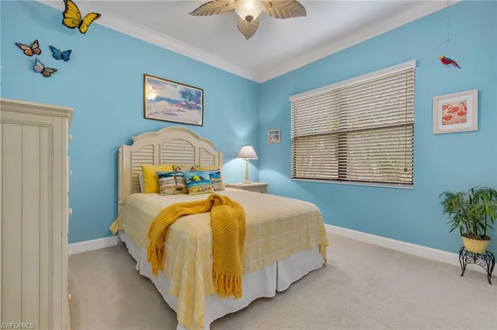 Carpeted bedroom featuring ceiling fan and ornamental molding