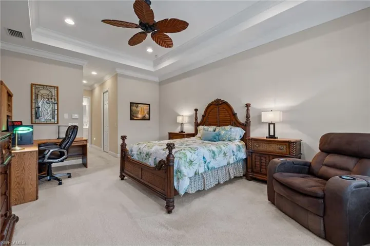 Carpeted bedroom featuring a tray ceiling, a closet, ceiling fan, and crown molding