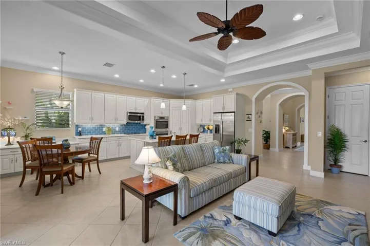 Living room with ceiling fan, light tile patterned flooring, and ornamental molding