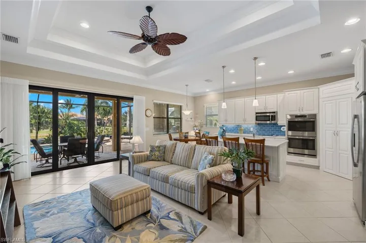 Living room with crown molding, light tile patterned flooring, and a raised ceiling