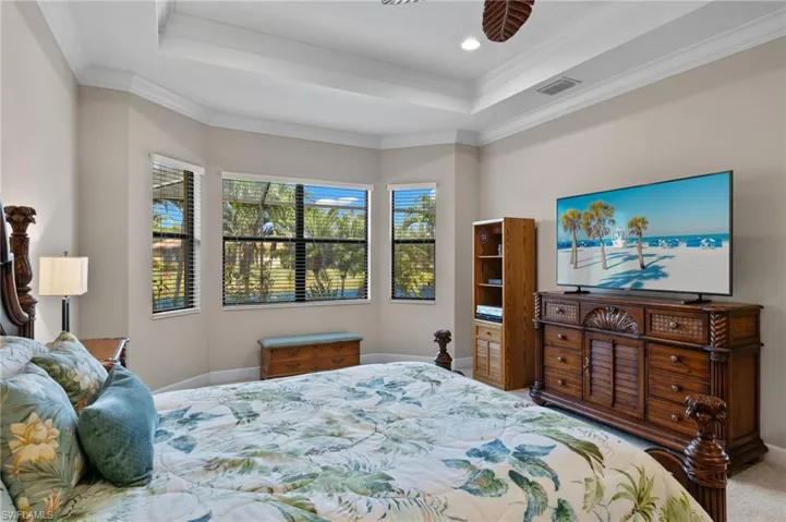 Bedroom with ornamental molding, a raised ceiling, and carpet flooring