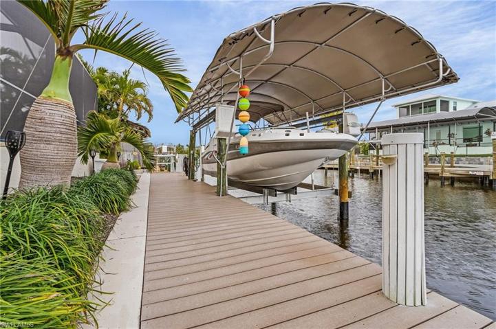 Composite dock, wrapped, capped, and covered pilings, covered boat lift with remote for lift, and fish cleaning station with water.