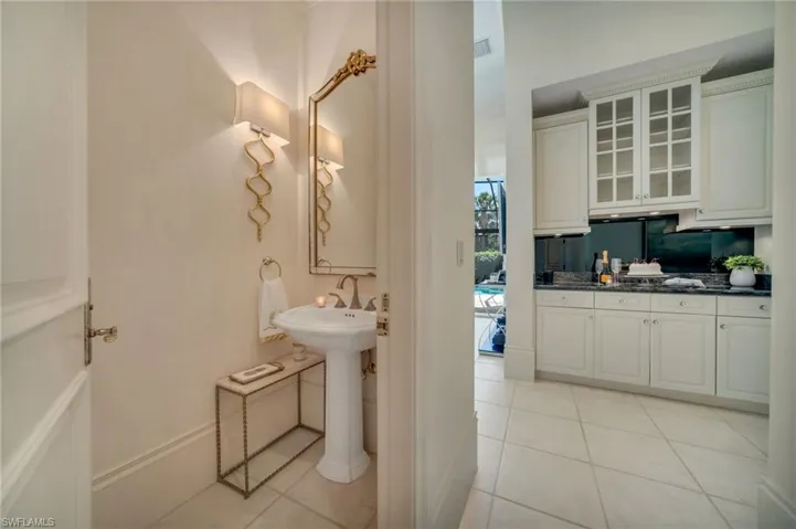 The bar has abundant storage and can be used as a serving area.  Guest powder room is elegantly equipped with Visual Comfort lighting.