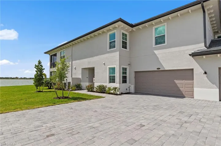 View of front of home featuring a garage, stucco siding, a front lawn, and decorative driveway