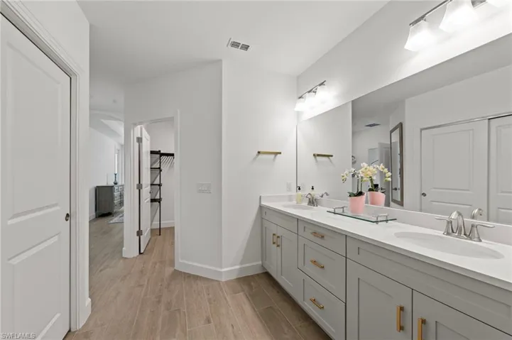 Bathroom featuring double vanity, wood finish floors, and a walk in closet
