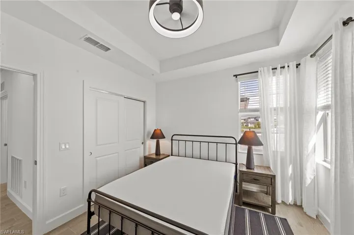 Bedroom featuring light wood-style floors, a closet, and a tray ceiling