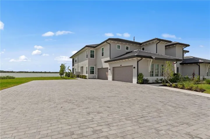 View of front of home with stucco siding, decorative driveway, an attached garage, and a water view