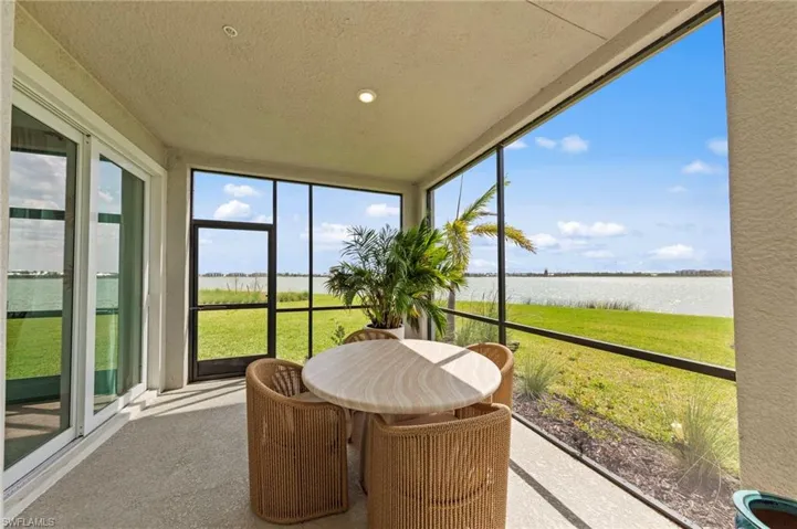 Sunroom / solarium with a water view, a textured ceiling, carpet flooring, and floor to ceiling windows