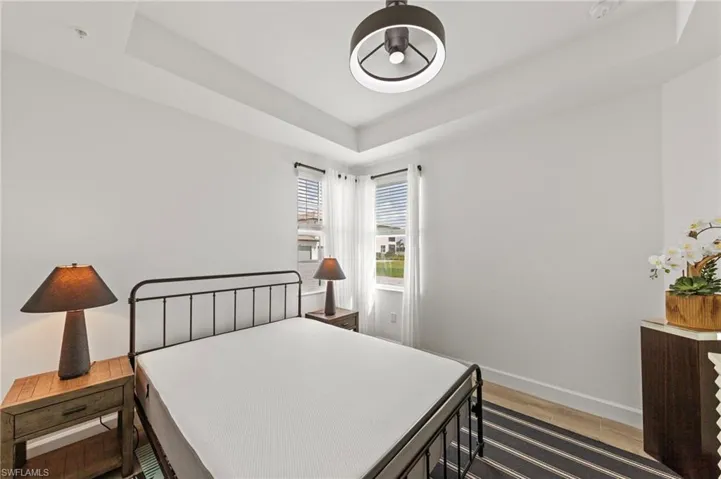Bedroom with a tray ceiling and light wood finished floors