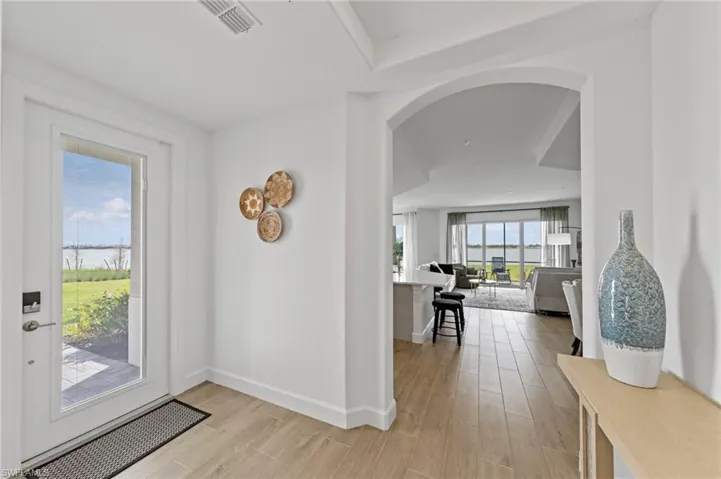 Foyer entrance with arched walkways and light wood-style floors