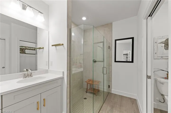 Full bath with a stall shower, vanity, wood tiled floors, and recessed lighting