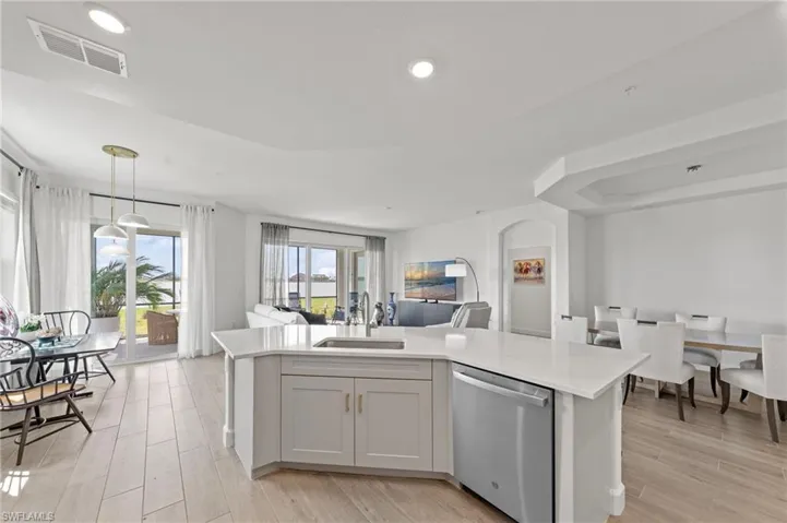 Kitchen with a kitchen island with sink, dishwasher, open floor plan, and light wood finished floors