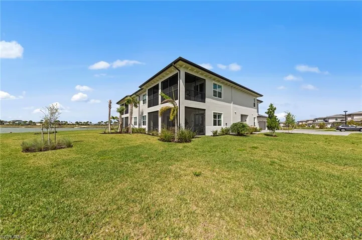 Rear view of house with a sunroom, a garage, a yard, and stucco siding