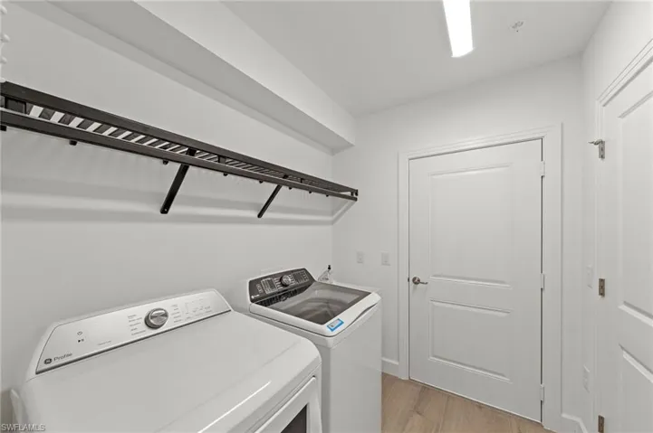 Laundry area with light wood-style flooring and washer and clothes dryer