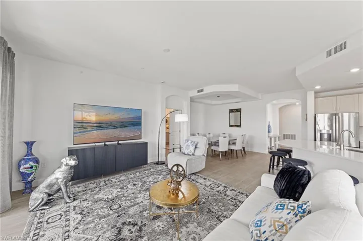 Living room featuring arched walkways, light wood-style floors, and recessed lighting