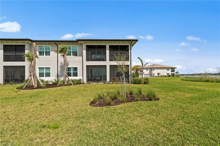 Back of property with a sunroom, stucco siding, and a lawn
