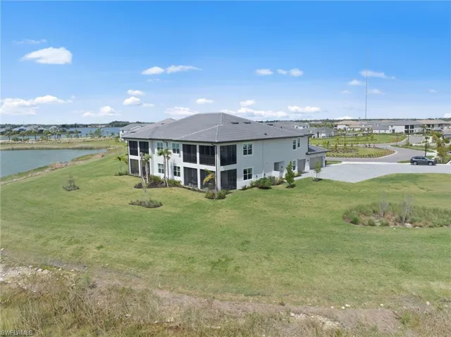 Rear view of property featuring a yard, a water view, and a sunroom