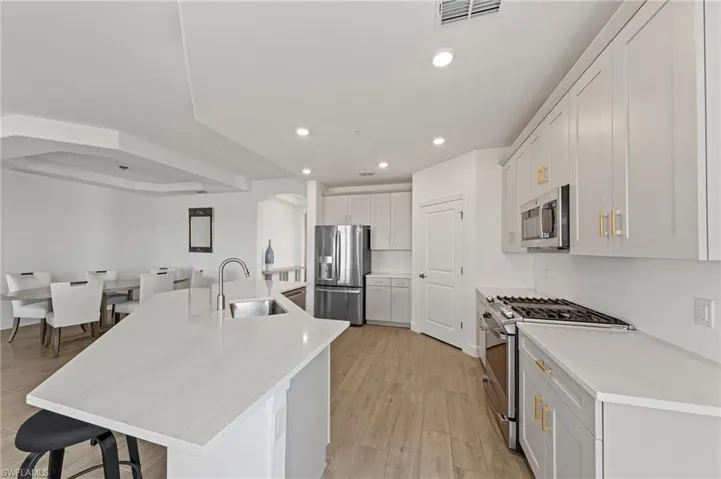 Kitchen featuring stainless steel appliances, a center island with sink, light wood finished floors, a breakfast bar, and recessed lighting