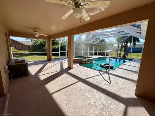 View of pool featuring an in ground hot tub, a covered patio, screen enclosure, and ceiling fan