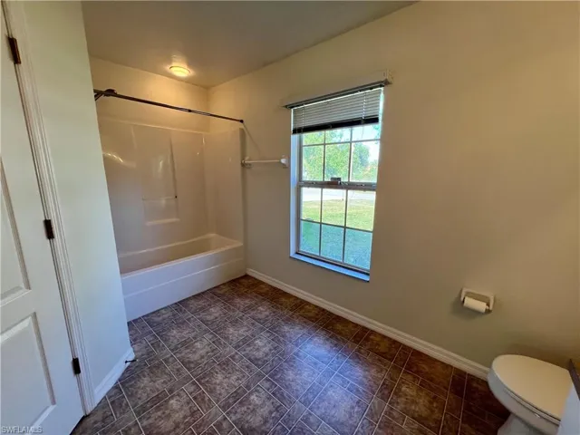 Bathroom with toilet and tub / shower combination and large walk in closet