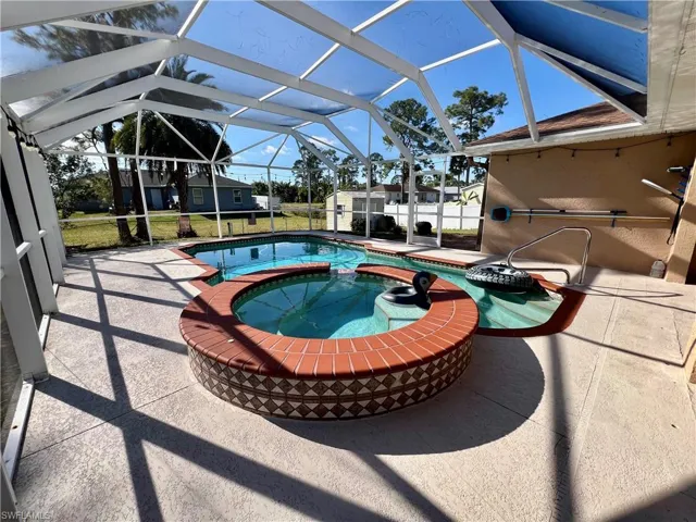 View of pool with an in ground hot tub, a patio, and screen  enclosure