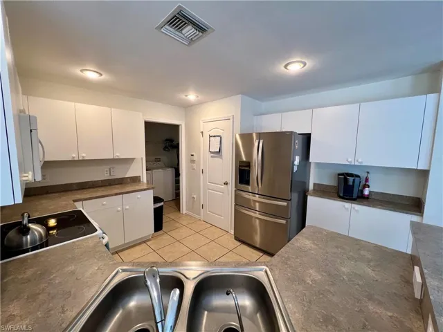 Kitchen featuring white cabinets, stainless French door  steel refrigerator with ice dispenser, range, dishwasher and built in microwave.