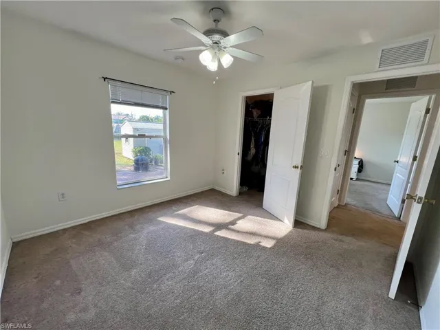 Guest bedroom with ceiling fan and a walk in closet