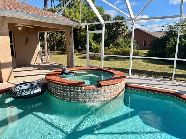 View of pool with ceiling fan, a lanai, a yard, and an in ground hot tub
