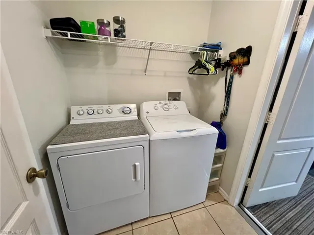 Laundry area featuring washing machine and clothes dryer and light tile patterned flooring