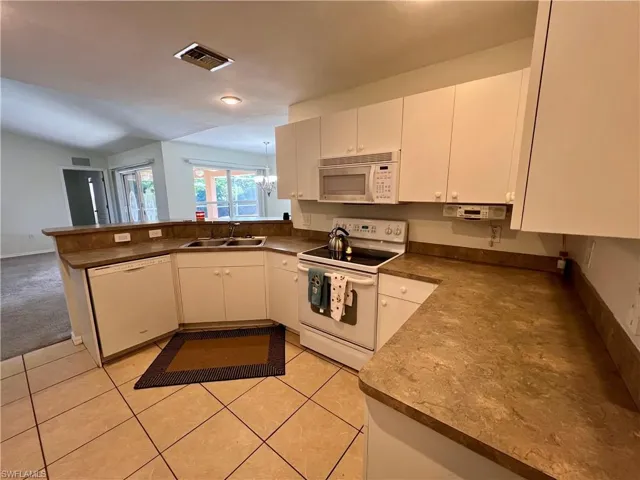 Kitchen featuring white cabinets, light tile patterned floors,  appliances, and sink