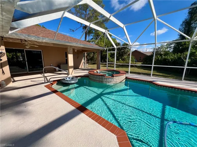 View of pool featuring a lanai, a patio area, and an in ground hot tub