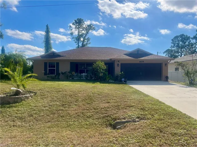 Single story home with a garage and a front yard