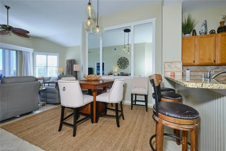 Dining space featuring vaulted ceiling, a ceiling fan, and light tile patterned flooring