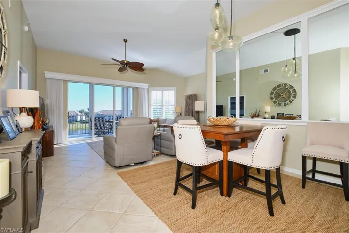 Dining area featuring light tile patterned flooring, vaulted ceiling, and ceiling fan
