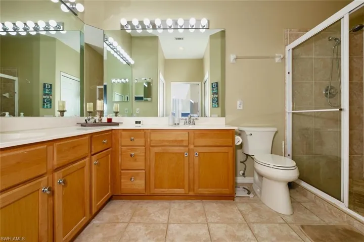 Bathroom with a stall shower, double vanity, and light tile patterned flooring