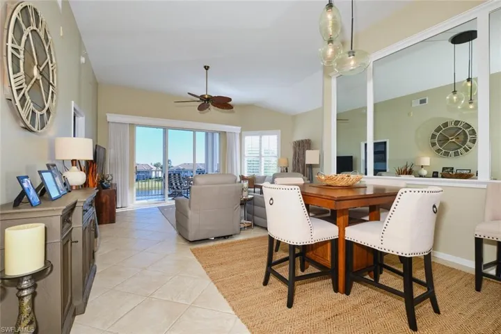 Dining area with vaulted ceiling, light tile patterned floors, and ceiling fan
