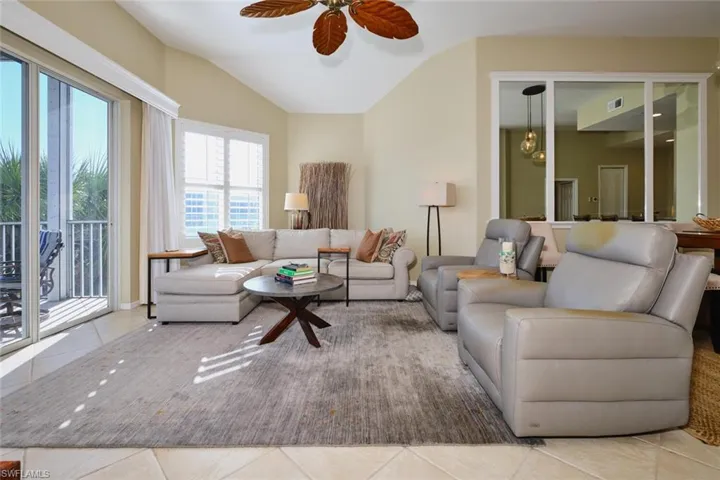 Living room with tile patterned floors, ceiling fan, and vaulted ceiling