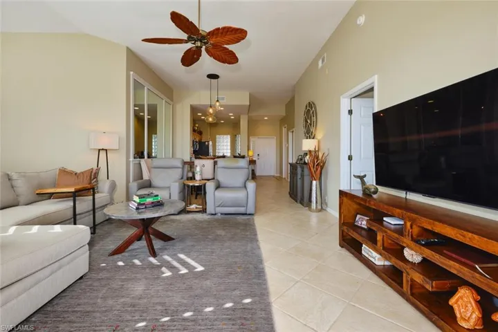 Living area featuring light tile patterned flooring, a ceiling fan, and hanging lights