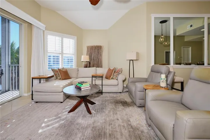 Living room featuring lofted ceiling, a ceiling fan, and tile patterned floors