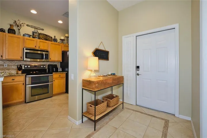 Kitchen featuring stainless steel appliances, light tile patterned flooring, decorative backsplash, wood finish cabinetry, and recessed lighting