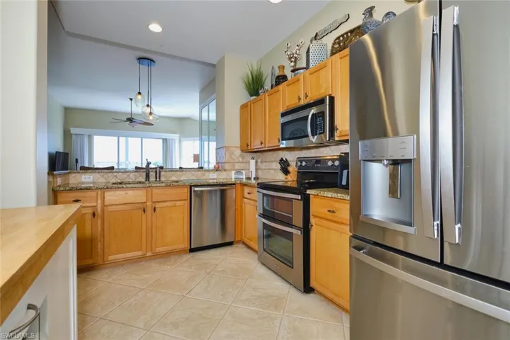 Kitchen with stainless steel appliances, light tile patterned floors, pendant lighting, butcher block countertops, and backsplash