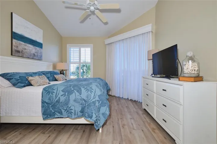 Bedroom featuring light wood-type flooring, lofted ceiling, and a ceiling fan
