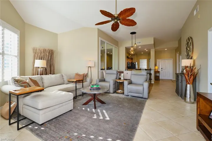 Living room featuring a ceiling fan, light tile patterned flooring, and lofted ceiling